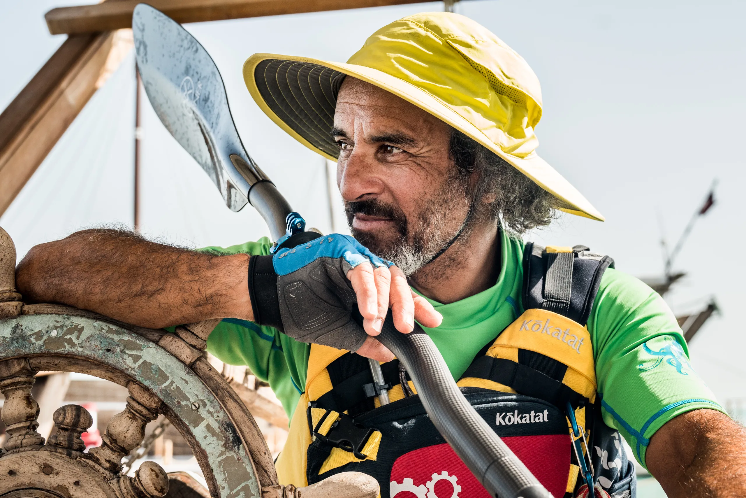 A paddler in a yellow hat resting on his paddle