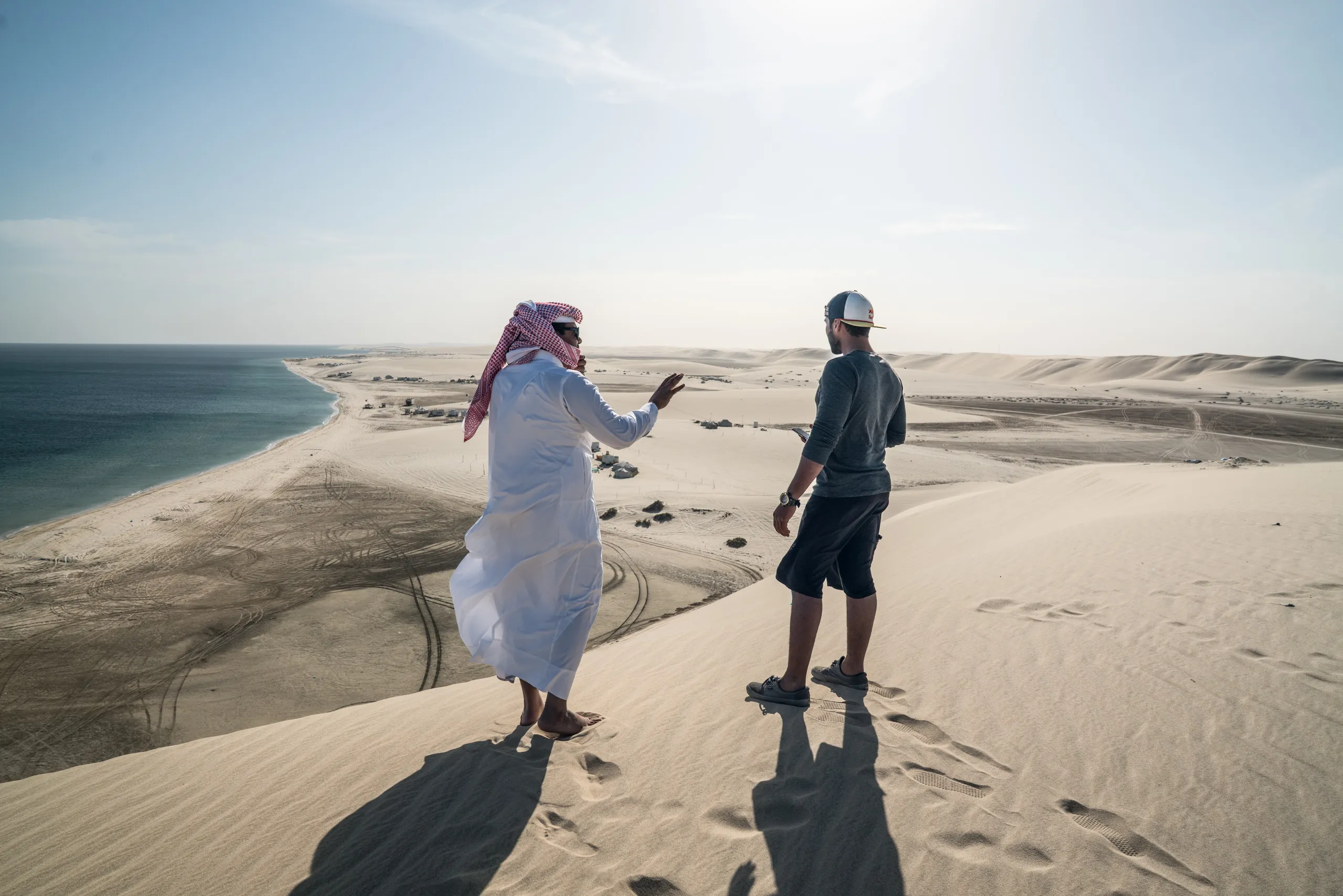 Two men talking on a dune above the sea