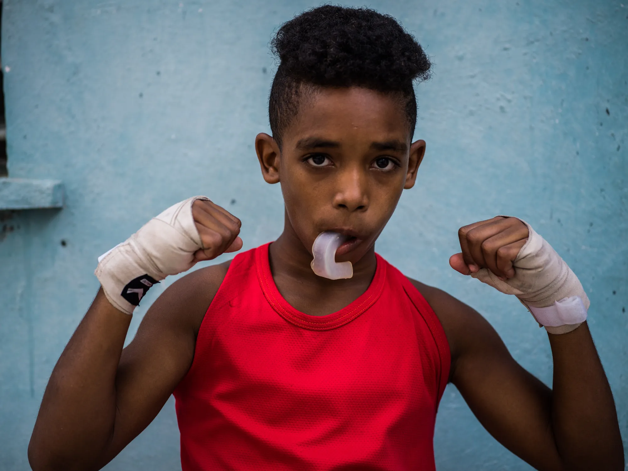 A young boxer flexing with his mouthguard out
